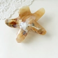 Detailed view of starfish claw clip with amber marble texture on white lace background - Starfish Yellow