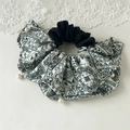 Dettaglio di scrunchie con motivo paisley e perle bianche su sfondo di pizzo chiaro - Bianco Paisley