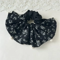 Dettaglio di scrunchie floreale nero con perle bianche su sfondo di pizzo bianco - Nero Floreale Ramo