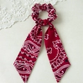 Detail eines roten Bandana-Haargummis mit langen Bändern auf schlichtem weißem Grund - Rot