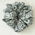 Detail eines weißen Scrunchies mit elegantem schwarzen Paisleymuster und weichen Stofffalten - Weiß Paisley Stil C