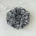 Macro detail of the silver laser fabric layers and metallic texture of the oversized scrunchie - Gray Laser Pleated