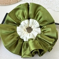 Detail van een premium oversized olijfgroene en beige satijnen scrunchie met textuur - Olijfgroen gemengd met gebroken wit