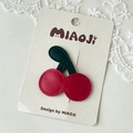 Detail of red leather cherry hair clip with green leaves and neat stitching design - Cherry