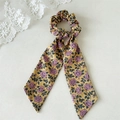 Détail d'un chouchou à imprimé fleuri avec de longs rubans sur un fond de dentelle blanche - Chouchou à Ruban Floral Jaune