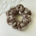 Detailopname van gebreide scrunchie met bruin ruitpatroon en wit kant accent - Beige Abrikoos