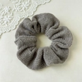 Gros plan du chouchou tricoté gris avec plis en tissu doux sur fond de dentelle blanche - Uni Gris