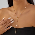 Nahaufnahme der goldenen Y-Kette mit weißen Perlen, Marienmedaille und Kreuzanhänger am Hals - Porträt Kreuz Perle Y-Form Quaste Halskette