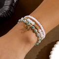 Set de pulseras multicapa con perlas blancas, cuentas de mármol azul y dije de lazo dorado - Verde