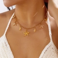Vista dettagliata di una collana dorata con stelle marine e conchiglie indossata al sole - Oro