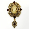 Macro shot of vintage cameo brooch with intricate gold openwork and red rhinestones - Champagne