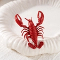 Dettaglio macro di un anello a forma di aragosta rossa su un vassoio di conchiglie bianche - Anello 3D