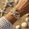 Golden starfish open bangle with white pearls and enamel on a beach sunset background - White Pearl Starfish (BR26Y0029-2)