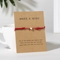 Rotes geflochtenes Armband mit goldenem Herzanhänger auf einer Make A Wish Karte - Rot