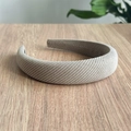 Primer plano de diadema de punto beige mostrando textura tejida sobre mesa de madera - Diadema / Caqui
