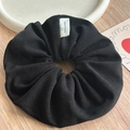 Detalle de coletero de punto negro con etiqueta hecha a mano sobre mesa de madera - Coletero / Negro