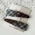Detailweergave van handgemaakte geruite stoffen haarklemmen met franjes op kaart - Blauw Koffie Plaid