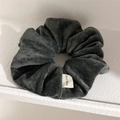Detailed macro view of charcoal grey velvet scrunchie with a white Hand Made woven label - Gray