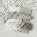 Detail van geruite stoffen haarspelden met franjes op beige kartonnen display - Beige Wit Plaid