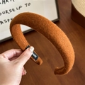 Detailed close-up of orange-brown wool headband with handmade label and soft texture - Caramel color