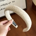 Detail showing the thick wool blend fabric texture and handmade tag of the headband - Beige