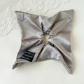 Macro detail of elegant champagne satin hair scrunchie with silk texture and woven label - Mocha