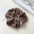 Dettaglio dell'elastico per capelli in velluto a coste marrone a pois su un libro - Elastico a Pois Velluto Caffè Scuro