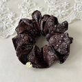 Dettaglio scrunchie marrone con stampa paisley, ciondolo dorato H e pizzo decorativo - Marrone