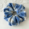 Detailopname van een blauw en wit geruite stoffen scrunchie met zachte katoenstructuur - Blauw Wit Geruit