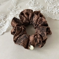 Dettaglio dell'elastico paisley marrone caffè con ciondolo a H dorato su pizzo - caffè