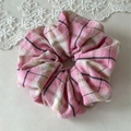 Detailopname van roze geruite scrunchie met zachte textuur op kanten ondergrond - Roze Wit Geruit