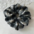 Close-up van zwart-witte ruitjes scrunchie met kant op een zachte beige achtergrond - Zwart-wit geruit