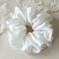 Macro shot of white satin scrunchie with silky folds and elegant lace background - White