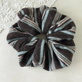 Detail view of striped knitted scrunchie fabric texture in brown, blue and pink tones - Brown