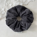Close-up of soft dark gray fabric scrunchie with woven texture and a side brand label - Large / Gray