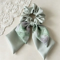 Detail eines Satin-Haargummis mit Blumenschleifen und eleganter Seidentextur - Ölgemälde Grün Band Haargummi