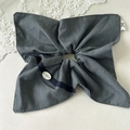 Detalle de coletero de lazo de tela gris con hebilla decorativa BOTANI y etiqueta lateral - Estilo Pañuelo