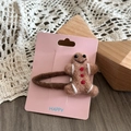Close-up of wool felt gingerbread man hair clip with intricate white details and a knit base - Cookie