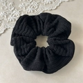 Detail of black wool scrunchie featuring thick textured knit fabric and elastic ruffles - Black