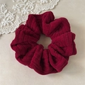 Close-up of thick burgundy corduroy scrunchie texture with high elasticity on marble - Burgundy