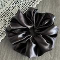 Close-up of thick dark brown satin hair scrunchie with subtle logo label on lace - Faux Leather Coffee Gray