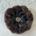 Detail van een pluche haarelastiek van bruin nepbont en zwart satijn op beige kant - Zwarte Pluche Rand