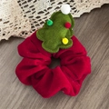 Détail du chouchou en velours rouge avec sapin de Noël vert sur fond de bois - Chouchou de Noël