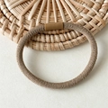 Élastique à cheveux marron avec texture côtelée sur fond décoratif en rotin tressé - Abricot Sergé
