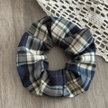 Detail shot of navy and beige herringbone plaid scrunchie on a wooden surface - Blue