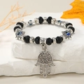 Detalle de pulsera de mano de Fátima y ojo turco sobre soporte de piedra blanca - Negro