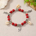 Primer plano detallado de la pulsera bohemia de cuentas rojas con dijes de mar y conchas - Rojo