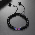 Vista macro di perline nere opache e accenti a freccia iridescenti su bracciale intrecciato - Arcobaleno