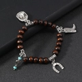 Detail of western cowboy charms including boots and lucky horseshoe on beaded bracelet - Coffee