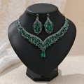 Detail of luxury gold jewelry set featuring green crystals and vintage V-shape necklace - Green